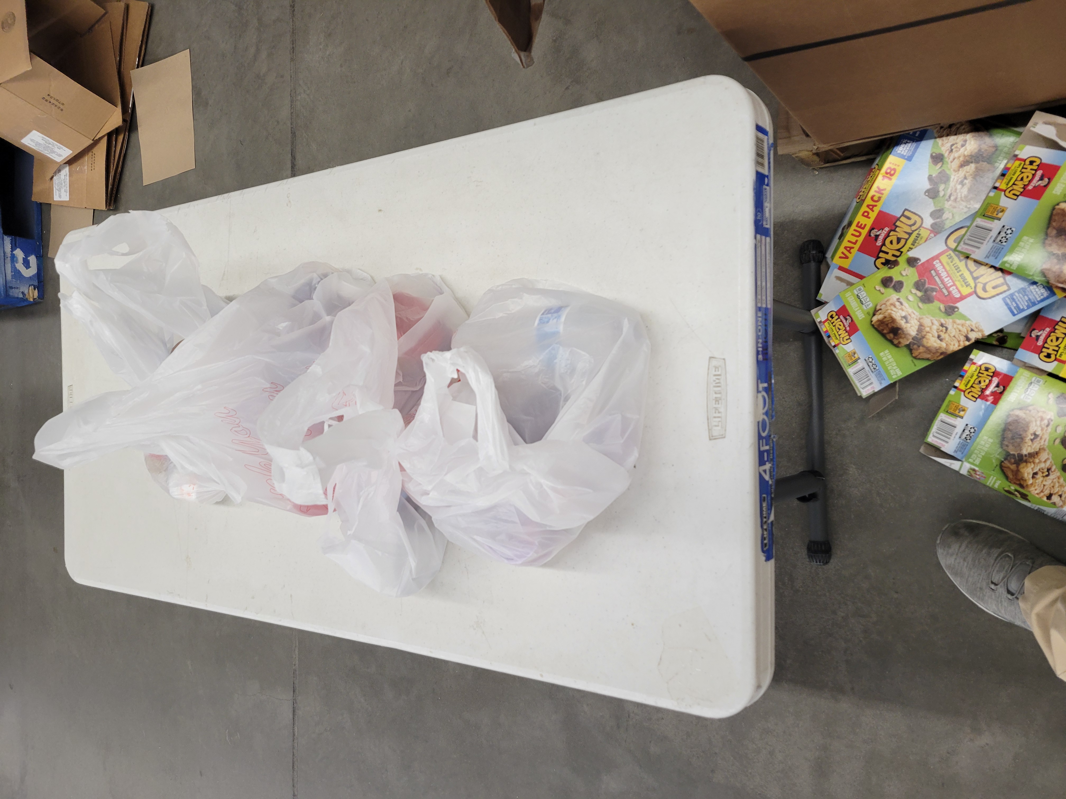 Plastic bags on a table with empty granola bar boxes next to it.